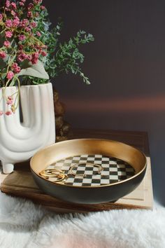 a vase with flowers in it next to a black and white checkerboard tray