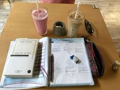 a table topped with glasses and notebooks next to two drinks on top of each other