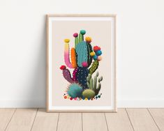 a colorful cactus art print hanging on a wall next to a wooden floor in front of a white wall