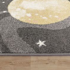 an area rug on the floor with a star and moon design in grey, yellow and white