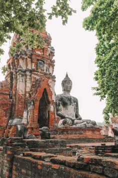 a buddha statue sitting on top of a stone wall