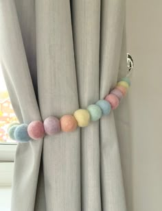 a curtain with some balls hanging from it's side and a window in the background