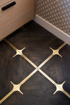 a wooden floor with four metal handles on it's sides and two drawers in the background