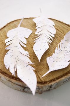 some white paper leaves are on a piece of wood with handwritten writing in it