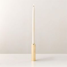 a white candle sitting on top of a table next to a black and gold object