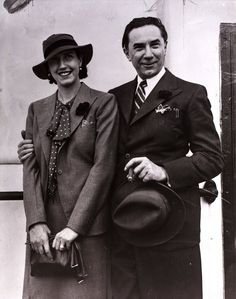 an old black and white photo of two people in suits standing next to each other