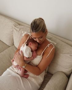 a woman sitting on a couch holding a baby