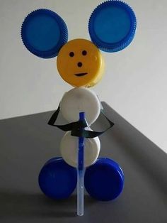 a plastic mickey mouse with blue and white cups on it's head, holding a toothbrush