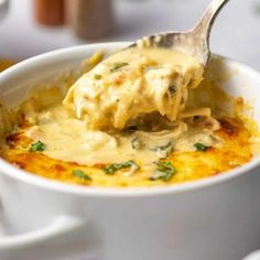 a spoon with some food in it on top of a white cup and saucer