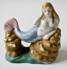 a ceramic figurine of a mermaid sitting on a rock