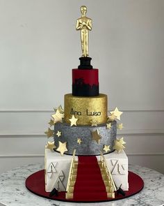 a three tiered cake with an oscar statue on top and stars around the edges