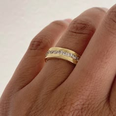 a person's hand with a gold ring and diamond set band on their finger