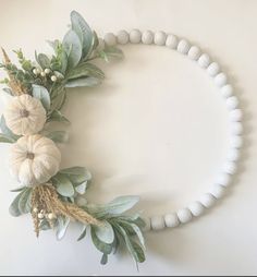 a white beaded necklace with flowers and greenery on the front is displayed against a white background