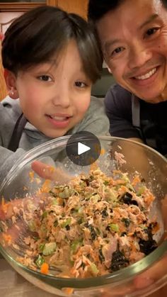 a woman and child are smiling while holding a bowl full of food in front of them