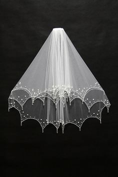 a white veil with pearls hanging from it's side on a black background,