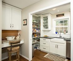 a kitchen with white cabinets and wooden floors