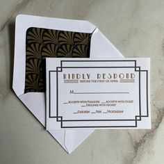 two envelopes with black and gold designs on them, one has a name card