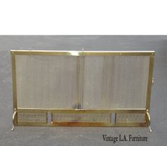 an antique brass fireplace screen on display in a parking lot with the words vintage la furniture written below it