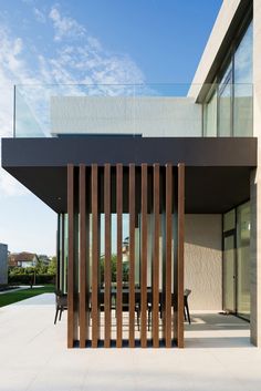 a modern house with wooden slats on the front and side walls, along with an outdoor dining area