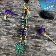 a close up of a necklace on a wooden surface with flowers in the foreground