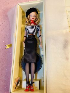 a barbie doll in a box with clothes and accessories on the shelf next to it