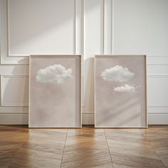 two framed pictures sitting on top of a hard wood floor next to a white wall