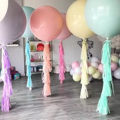 several balloons with tassels hanging from them in a room filled with other balloons