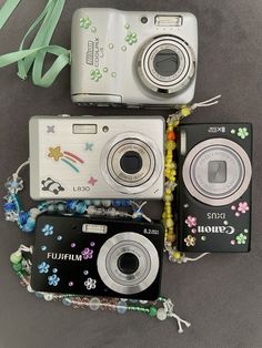 three cameras sitting next to each other on top of a table with ribbons around them