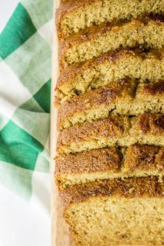 a loaf of bread sitting on top of a cutting board next to a green and white checkered napkin