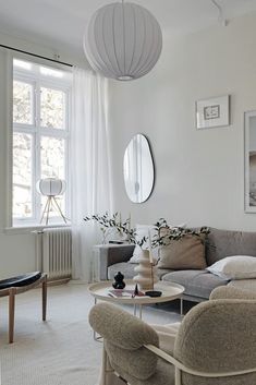 a living room filled with furniture and a round mirror