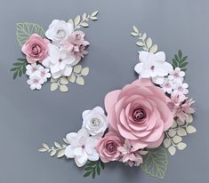 three paper flowers on a gray surface with leaves and branches in the middle one is pink, the other is white