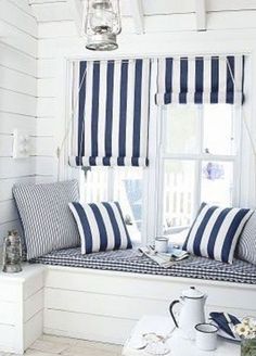 blue and white striped pillows on a bench in front of a window with coffee mugs