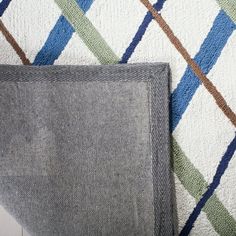 two pieces of fabric sitting on top of a wooden floor next to a rug with different colored stripes