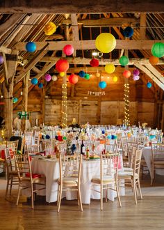 tables and chairs are set up with colorful paper lanterns hanging from the ceiling