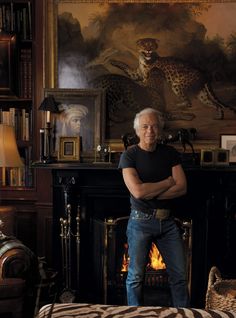 a man standing in front of a fire place next to a zebra print bed spread