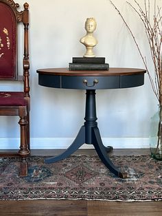 a small table with a book on it in front of a chair and a vase