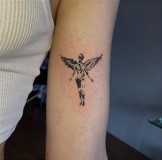 a woman's arm with a tattoo of an angel holding a cross on it