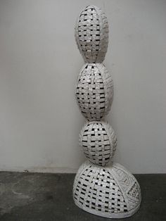 three wicker balls stacked on top of each other in front of a white wall