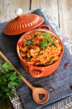 a bowl filled with food sitting on top of a blue cloth next to a wooden spoon