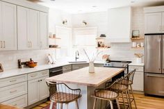 a kitchen with white cabinets and stainless steel appliances, including an island in the middle