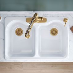 a kitchen sink with two golden faucets on the side and a marble counter top