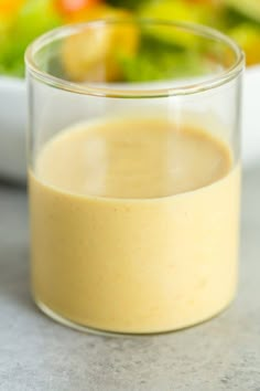 a glass filled with liquid next to a bowl of salad