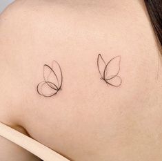 the back of a woman's shoulder with two small tattoos on her left side