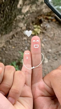 two fingers with faces drawn on them and one has a ring in the shape of a heart