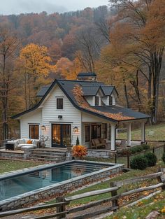 a white house with a pool in front of it and lots of trees surrounding it