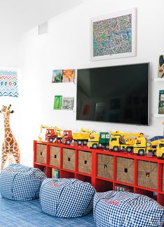 a child's playroom with toys on the floor and a large tv mounted above it