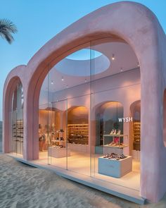 the inside of a store with pink walls and arches on the beach at night time