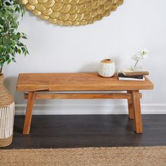 a wooden bench sitting next to a potted plant on top of a hard wood floor