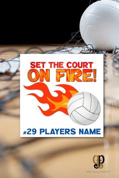 there is a sign that says set the court on fire and two volleyballs next to it