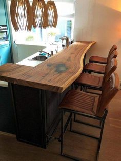 a kitchen island made out of wood with four chairs at the counter and lights hanging from the ceiling